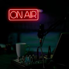 a red neon sign that reads on air above an electronic equipment set up in the dark