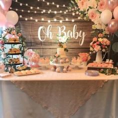 a table topped with lots of cakes and desserts next to a sign that says oh baby