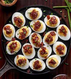 deviled eggs with bacon and ketchup in a cast iron skillet on a wooden table