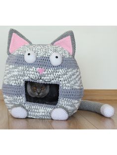 a cat is sitting in a crocheted kitty bed with its eyes wide open