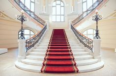 a red carpeted staircase leading up to an arched window