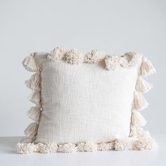 a white pillow with pom - poms on the bottom and one in the middle