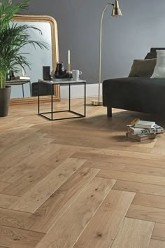 a living room with wood flooring and a black couch next to a mirror on the wall