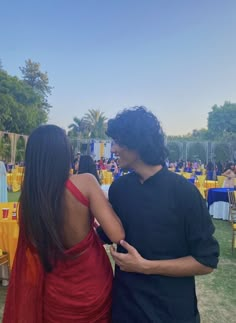 two people standing next to each other in front of tables with yellow and blue cloths