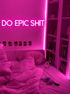 a bed in a room with pink lighting and pictures on the wall next to it