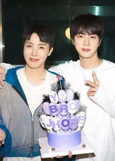 two young men holding a birthday cake together