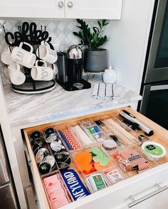 an open drawer in a kitchen with utensils and other items on the counter