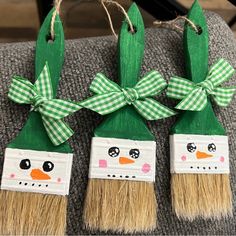 three green and white painted christmas decorations with bows on them, sitting on a chair