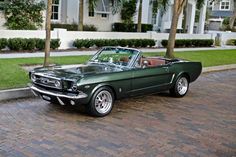 an old green mustang parked on the side of the road in front of a building