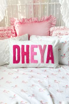 a pillow that says dhyea on it sitting on top of a white bed