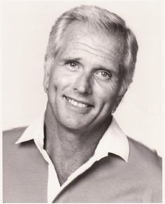 a black and white photo of a man with blonde hair smiling at the camera while wearing a polo shirt