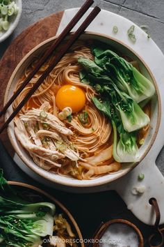 a bowl of ramen with an egg in it and chopsticks on the side