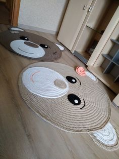 two rugs with faces on them sitting on the floor in front of a cabinet