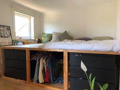 a bed with drawers underneath it and clothes on the bottom shelf in front of it