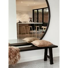 a large round mirror sitting on top of a wooden bench next to a table and chairs