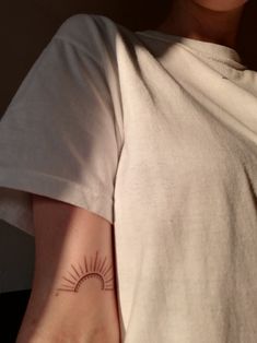 a woman's arm with a small sun tattoo on the left side of her arm