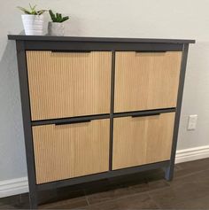 a cabinet with three drawers and two plants on top of the bottom one is made out of bamboo