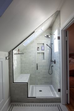 a walk in shower sitting next to a white door and window on top of a tiled floor