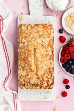 a cake with almonds, strawberries and yogurt on a pink table