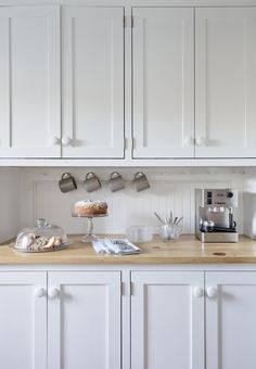 a kitchen with white cabinets and wooden counter tops, including a cake on a plate