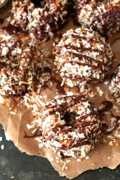 chocolate covered doughnuts with sprinkles and coconut flakes on parchment paper