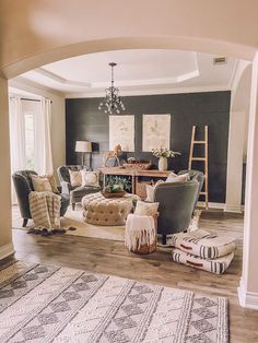 a living room filled with furniture and a chandelier hanging from the ceiling in front of a doorway