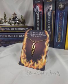 "Throne of Glass Series Inspired necklace with quote \"She was the heir of ash and fire, and she would bow to no one.\" And a handmade jewelry backing design :)  Perfect for the book lover in your life, this featured a gold flame necklace, with a vibrantly designed flame backing and quote from Heir of Fire. Upgrade to the Bundle for even more!  Includes: Flame Necklace, Tote Bag, Bookmark, Red scrunchie and Flame hair clip Main listing available here: https://www.etsy.com/listing/1354818840/thro Flame Necklace, Heir Of Fire, Flame Hair, Quote Fashion, Throne Of Glass Quotes, Red Scrunchie, Glam Studio, Throne Of Glass Series, Book Quote