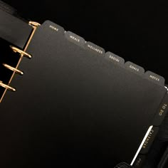 a black binder with gold trim on top of a black book cover that is open