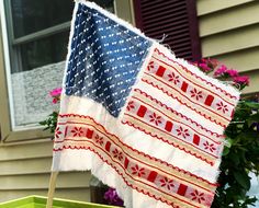 an american flag on a stick in front of a flower box with flowers and potted plants