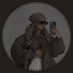 a woman taking a selfie in front of a mirror wearing sunglasses and a hat