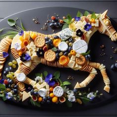 a horse made out of crackers and cheeses on a black plate with flowers