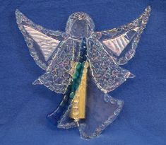 an angel figurine made out of glass on a blue background with gold and green accents