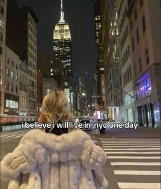 a woman in a white fur coat is standing on the street with her back to the camera