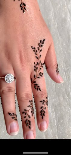 a woman's hand with henna tattoos on it and a diamond ring in the middle