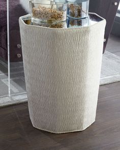 a round storage basket with jars and nuts in it on the floor next to a window