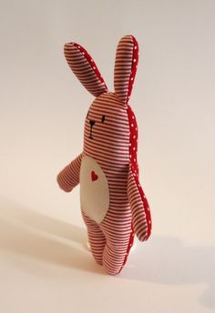 a red and white striped stuffed animal with a heart on it's chest, standing upright