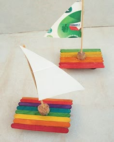 two small boats made out of popsicle sticks with a flag in the back ground