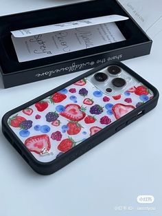 an iphone case with strawberries and berries painted on the back is sitting in a box