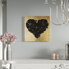 a heart shaped painting on the wall above a mantle with candles and flowers in vases