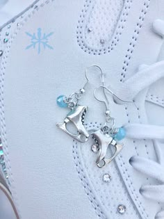 two pairs of silver and blue earrings on top of a pair of white tennis shoes