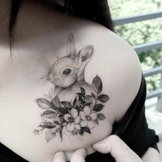 a woman with a tattoo on her chest holding flowers and a bunny in the center