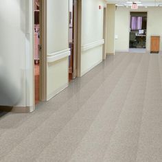 an empty hospital hallway with white floors and doors