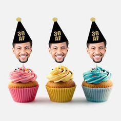 three cupcakes with birthday hats on top of them, and the faces of two men