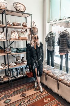 a woman sitting on a bench in front of a display of handbags and purses