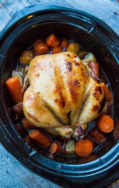 a chicken in a slow cooker with carrots and potatoes