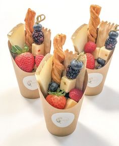 three cups filled with assorted fruit and cheeses on top of each other,