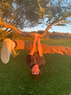 a person upside down in the grass under a tree