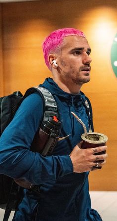 a man with pink hair is holding a cup