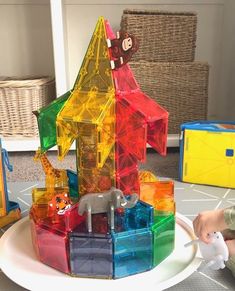 a toy house made out of plastic blocks on a table with other toys around it