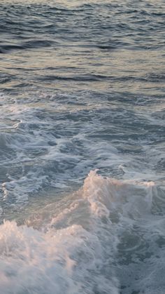 a man riding a surfboard on top of a wave in the ocean at sunset